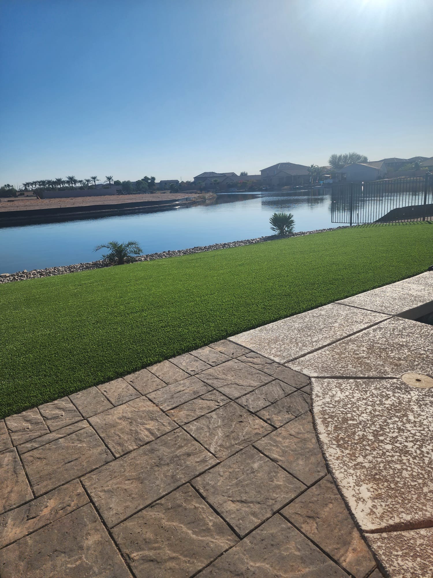Completed patterned outdoor patio beside turf and water
